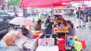 假期降雨，游客撑伞排队等美食