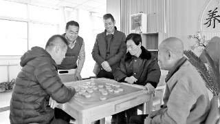 西峰区肖金镇综合养老服务中心工作人员陪老人下棋。